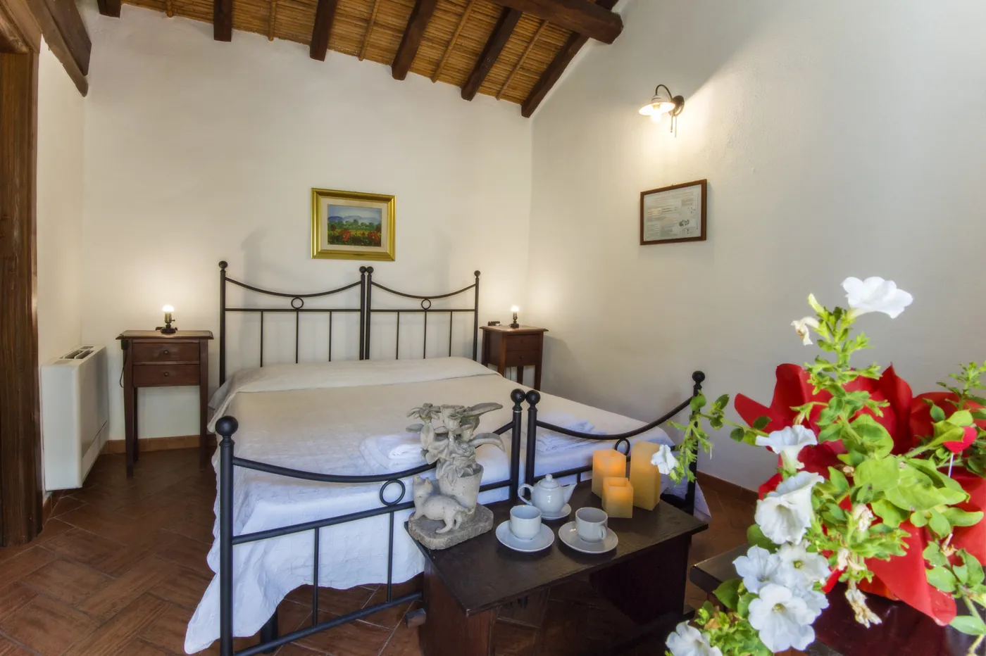 Camera doppia con letto matrimoniale in ferro battuto e fiori alla finestra