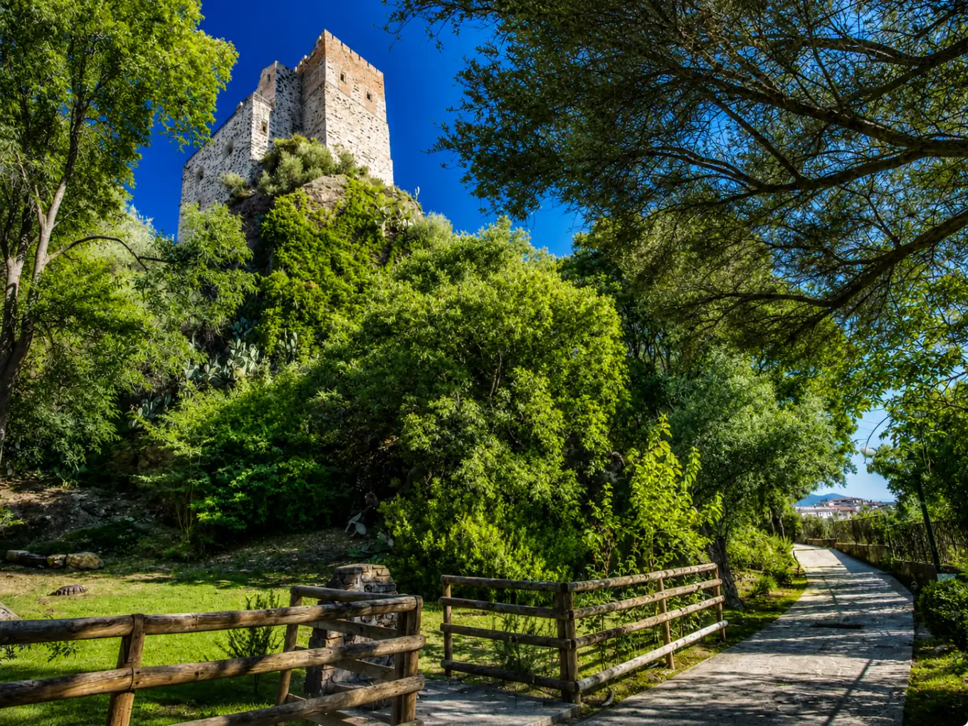 La torre del Castello Malicas tra il verde, lungo il viale d'ingresso